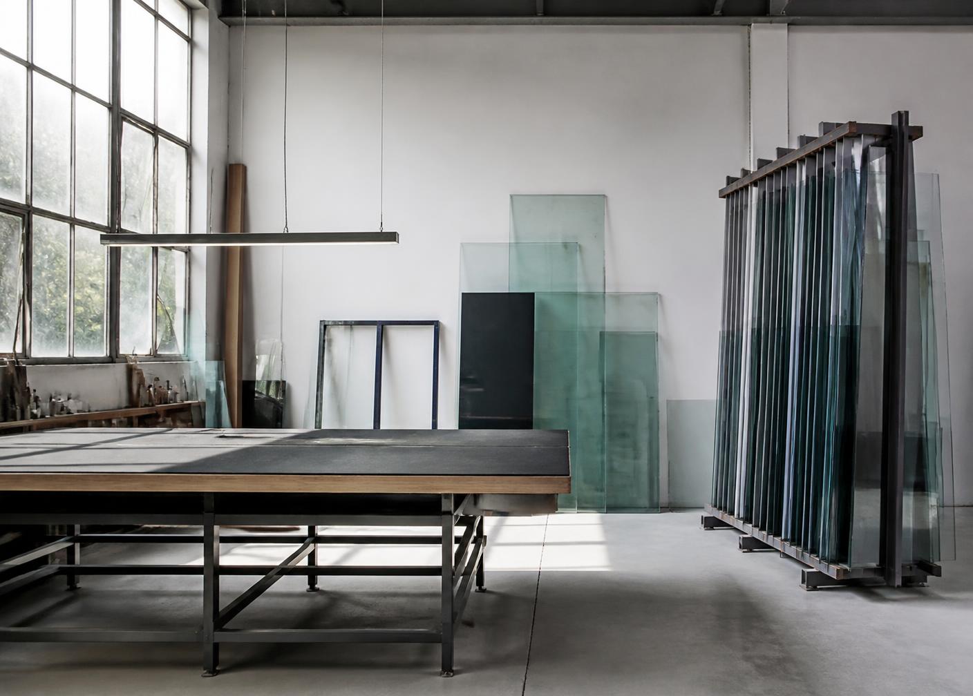 Glass panels racked beside a cutting table in the Prad Glass workshop